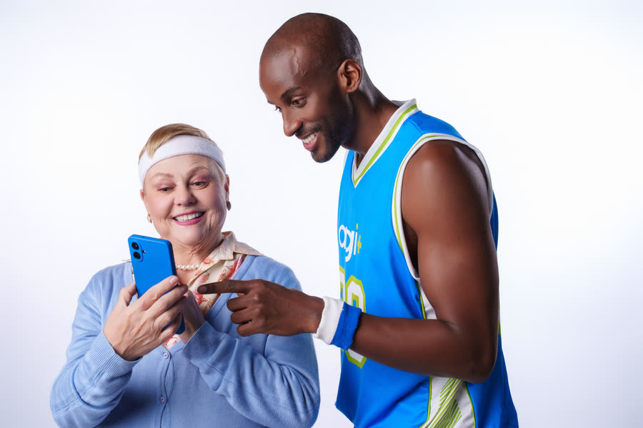 Senhora e jogador de basquete olhando um celular em fundo branco de estúdio, campanha do Agibank
